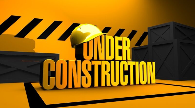 Image features a yellow hard hat on top of yellow 3D letters that read, 'UNDER CONSTRUCTION.' In the background are black tire tracks on bright yellow walls.